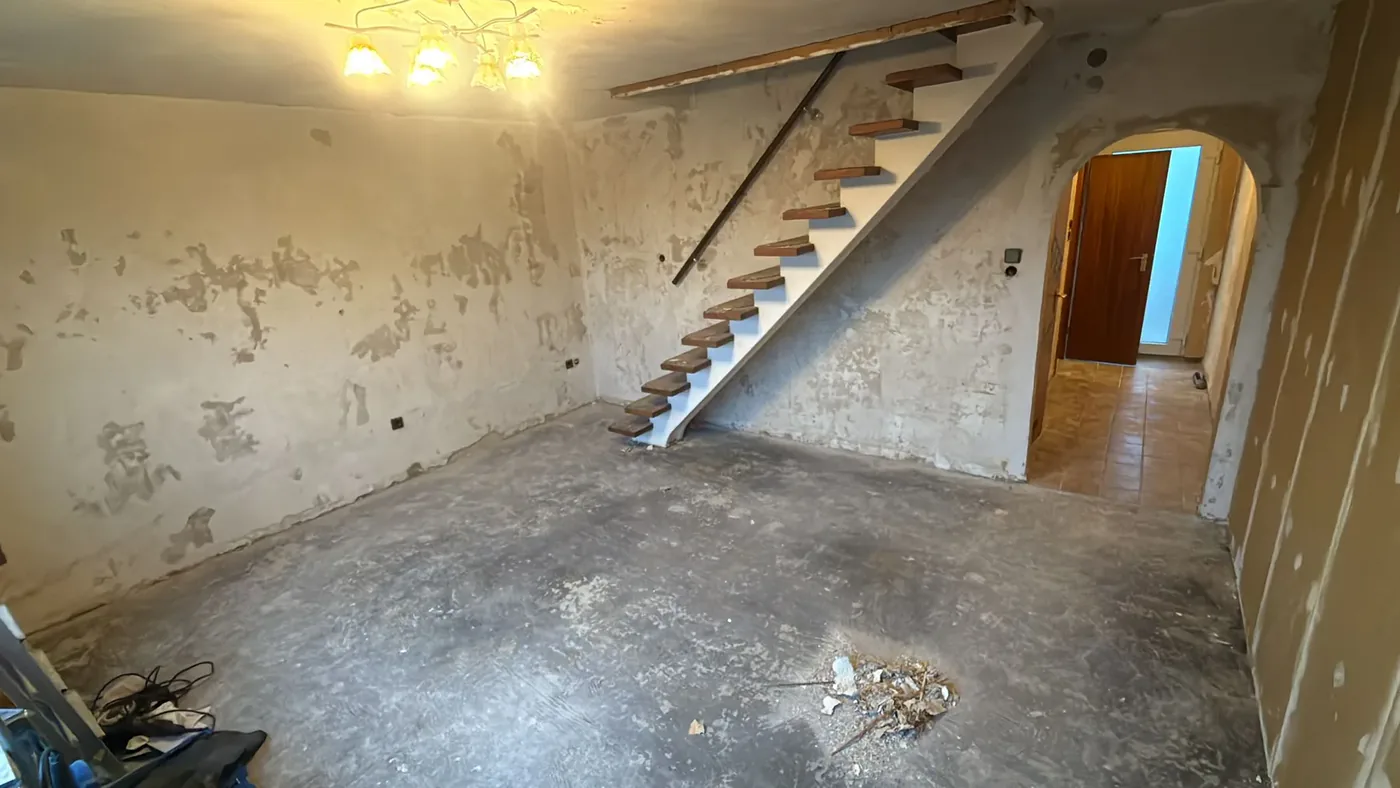 Treppenaufgang der Maisonette-Wohnung in einem Neubaugebiet vor der Renovierung mit abgeschlagenem Putz und rohem Estrich