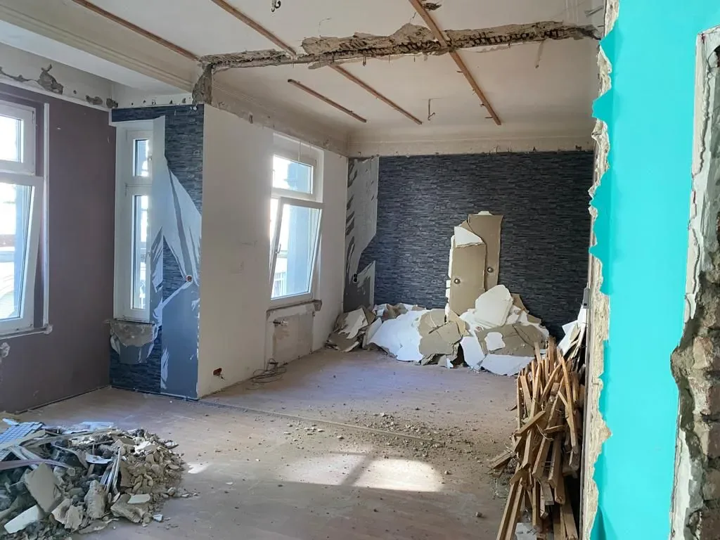 Wohnraum im Altbau im Rückbau, entfernte Wandverkleidung, offene Decke und Bauschutt auf dem Boden
